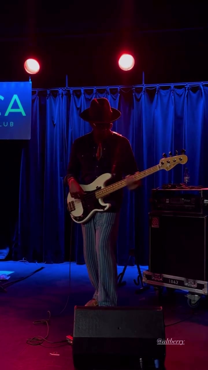 Al Berry playing bass beneath red and blue stage lights