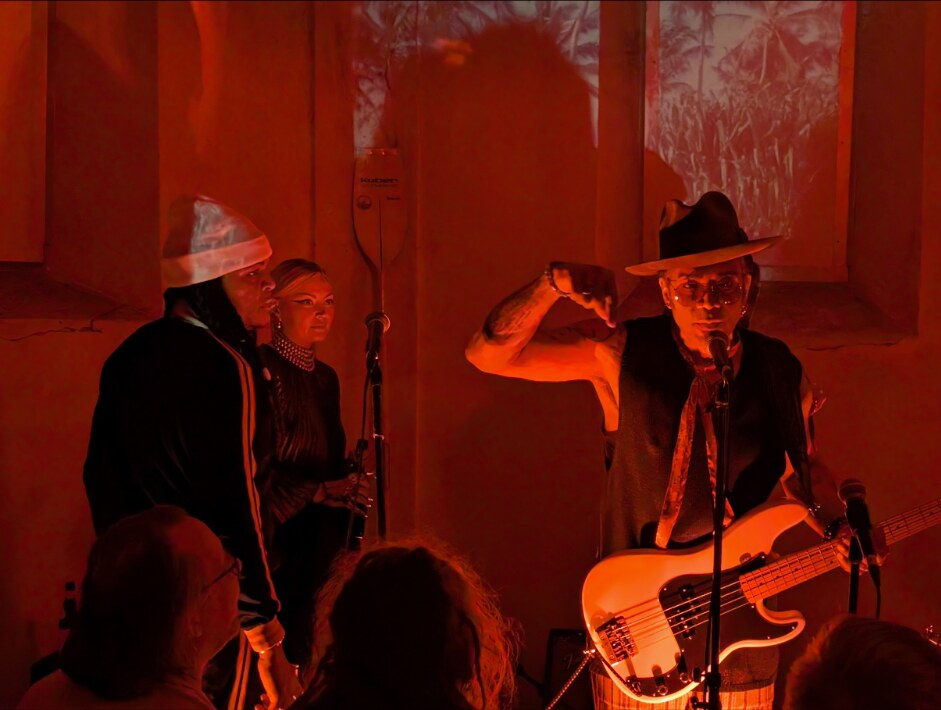 Al Berry performing with singers in a red-lit intimate venue